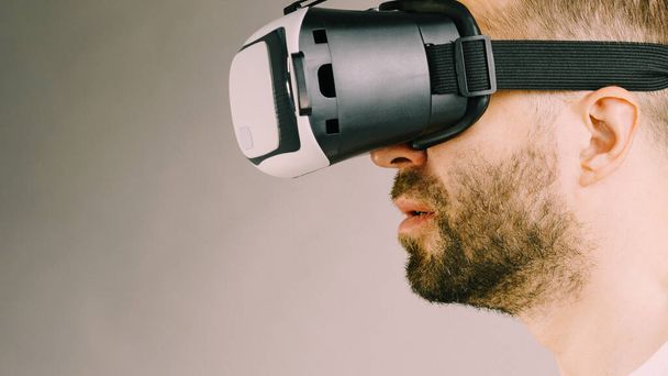 Un adulto con la barba corta che esplora la realtà virtuale indossando occhiali VR per diventare tecnologico. Studio shot vista laterale. - Foto, immagini