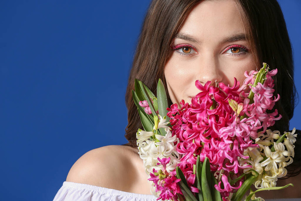 Beautiful young woman with hyacinth flowers on color background - Fotografie, Obrázek