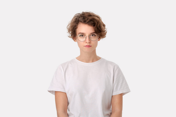 Znepokojená mladá žena v bílé košili a brýlích hledící pozitivně do kamery izolované nad bílým pozadím. Koncept myšlení - Fotografie, Obrázek