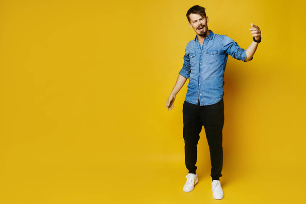 Yes, he did it. Stylish happy bearded man raising hands and shouting, posing in full length on the yellow background, isolated with copy space on the left - Photo, Image
