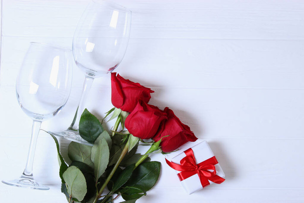 Rotwein, Herzen, rote Rosen und Geschenke auf farbigem Hintergrund von oben. - Foto, Bild