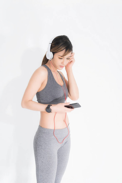 Fitness woman listening to music wearing white music headphones, enjoys sports and healthy lifestyle isolated on a white background. She is relaxing and happiness. - Foto, imagen