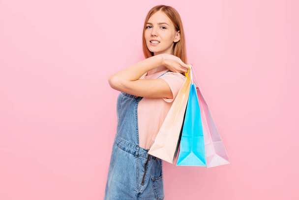 Attractive young stylish girl shopper holds shopping bags after shopping on an isolated pink background - Foto, Bild