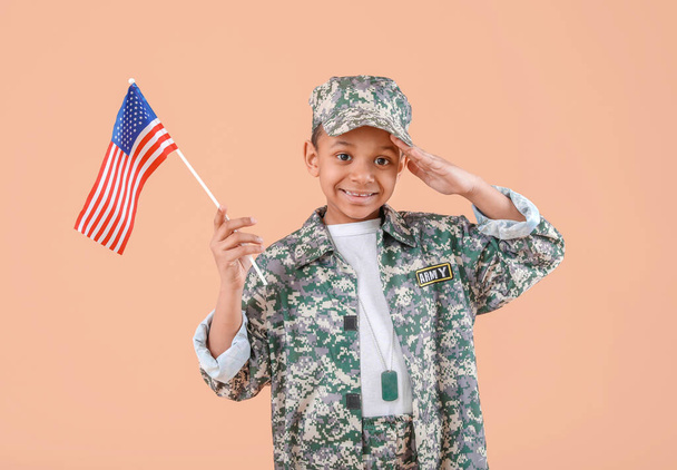 Pequeno soldado afro-americano saudando com bandeira dos EUA no fundo da cor
 - Foto, Imagem