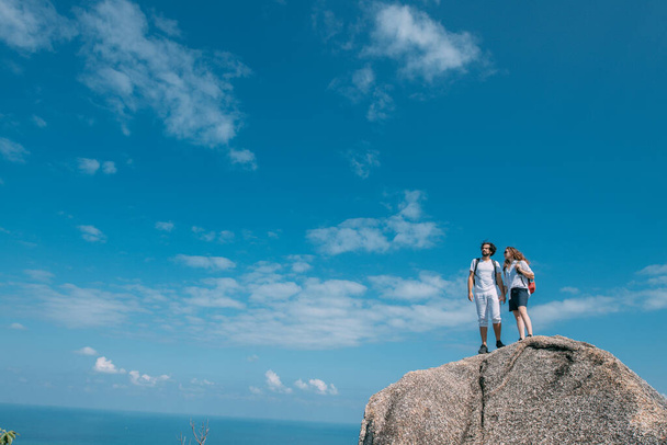 Een koppel staat op een rots op een uitkijkpunt met een episch uitzicht op de oceaan. Een populaire toeristische bestemming. Geliefden op vakantie in de tropen. Huwelijksreis in de tropen. - Foto, afbeelding