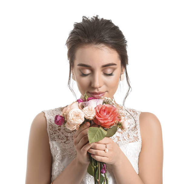 Young bride with beautiful hairdo and flowers on white background - Photo, Image