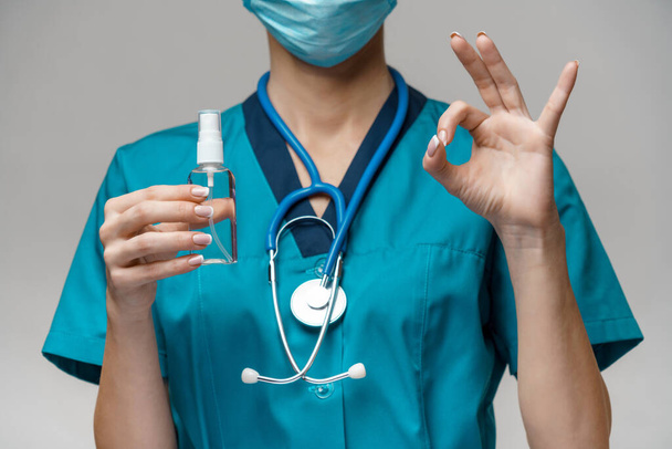 medical doctor nurse wearing protective mask - holding bottle of sanitizing spray or gel - 写真・画像