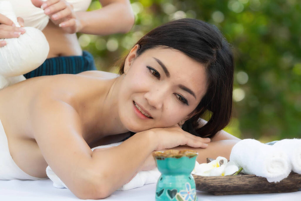 Bonita jovem mulher asiática desfrutando de massagem ao ar livre no salão de spa, dia
. - Foto, Imagem