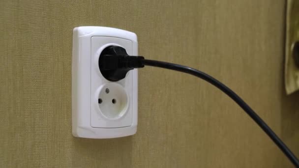 Male hand Disconnect the power supply cable into electrical outlet on a wall in a room. - Footage, Video
