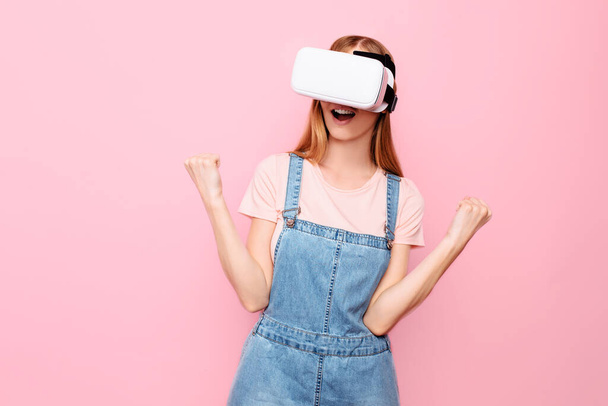 Young beautiful stylish woman with virtual reality glasses, on an isolated pink background - Fotografie, Obrázek