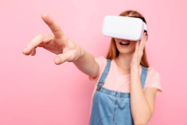 Young beautiful stylish woman with virtual reality glasses, on an isolated pink background - Fotó, kép