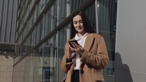 beautiful business woman using smartphone texting walking in corporate office typing text messages on mobile phone checking emails successful female executive at work 4k footage - Materiał filmowy, wideo