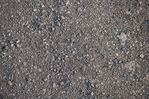 Background image of the surface covered with small gravel on the ground. Wallpaper. Substrate for text. Detailed texture of fine pebbles on the ground. The surface of the hiking trail. Top view. - Photo, Image