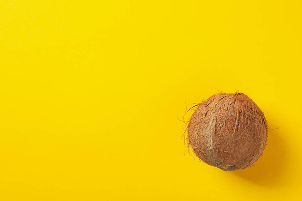 Whole coconut on yellow background, top view - 写真・画像