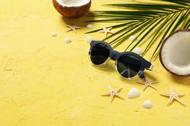 Морские звезды, кокос, пальмовая ветвь и солнцезащитные очки на желтом фоне, место для текста
 - Фото, изображение