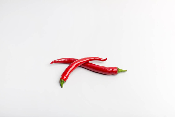Juicy red hot chilli peppers on a white background stacked next - Foto, Imagen