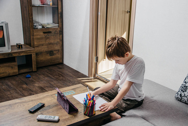 Un niño se sienta en casa aislado y aprende en línea
 - Foto, Imagen