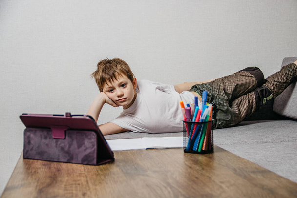 Un niño se sienta en casa aislado y aprende en línea
 - Foto, imagen