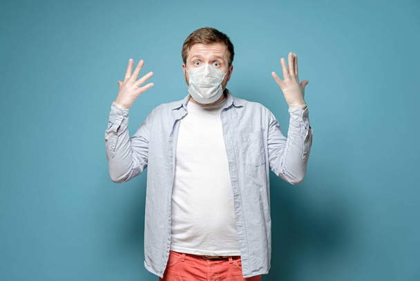 Mann mit medizinischer Maske und Latexhandschuhen blickt verängstigt in die Kamera. Sicherheitskonzept bei gefährlichen Viren und Pandemien. - Foto, Bild