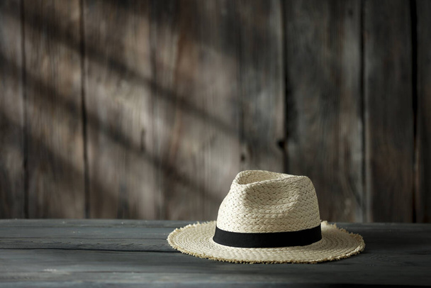 Wooden table with space for your decoration. Composition of straw hat with wooden retro wall and shadows of sun light. Copy space for your decoration.  - 写真・画像