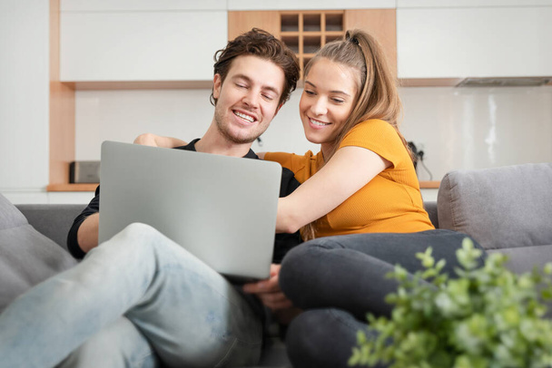 Couple utilisant Internet à domicile rapide avec ordinateur portable. Femme et homme sur canapé dans le salon - Photo, image