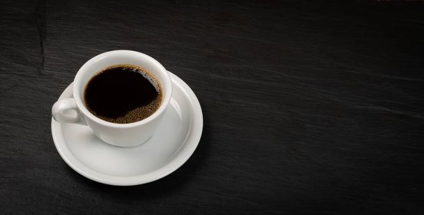 Hot coffee cup op zwarte stenen achtergrond met copyspace. Witte koffie of mok met warme drank topview - Foto, afbeelding