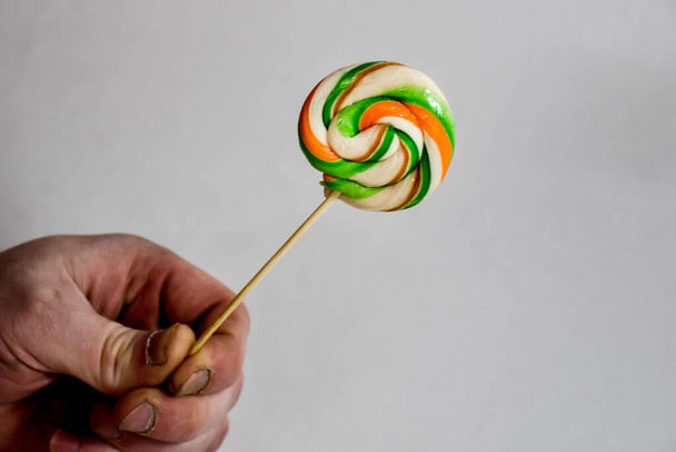 colorful spiral Lollipop on a stick held in the hand - Fotoğraf, Görsel