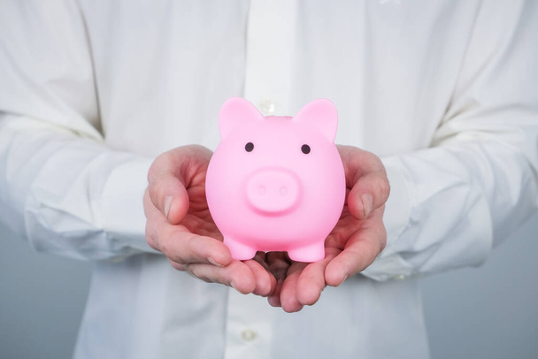 Pink piggy bank in mans hands. Concept of saving and earning money, investments.  - Photo, Image