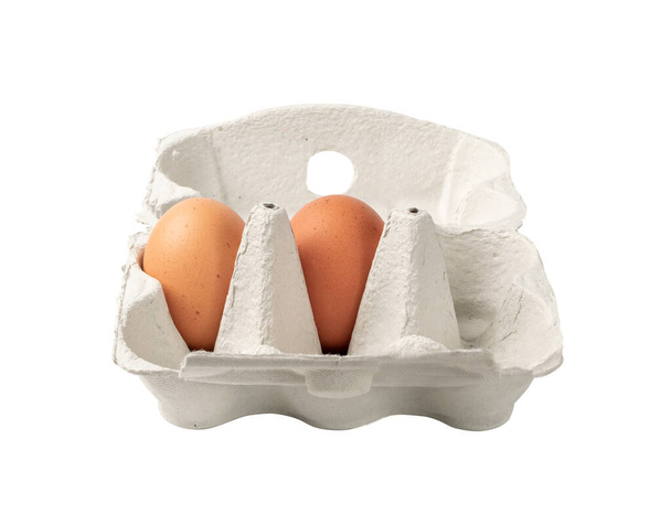 Открытая коробка с двумя целыми коричневыми яйцами, изолированными на белом фоне, с дорожкой обрезки. Свежие органические куриные яйца в упаковке или контейнере для яиц
 - Фото, изображение