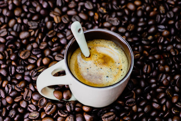 Taza de café con granos de café tostados sobre fondo rojo, concepto de café, foto de café de cerca - Foto, imagen