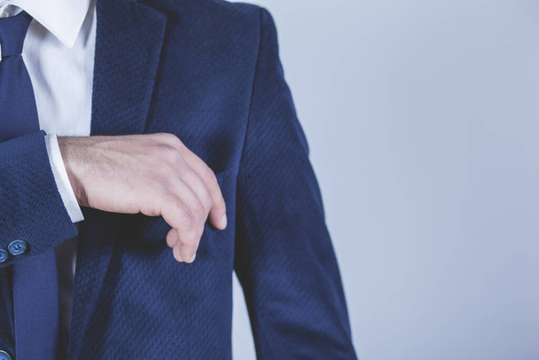 man hand in suit pocket on grey background - Фото, зображення