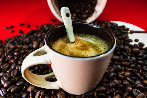 Tasse à café avec grains de café torréfiés sur fond rouge, concept de café, photo de café de gros plan - Photo, image