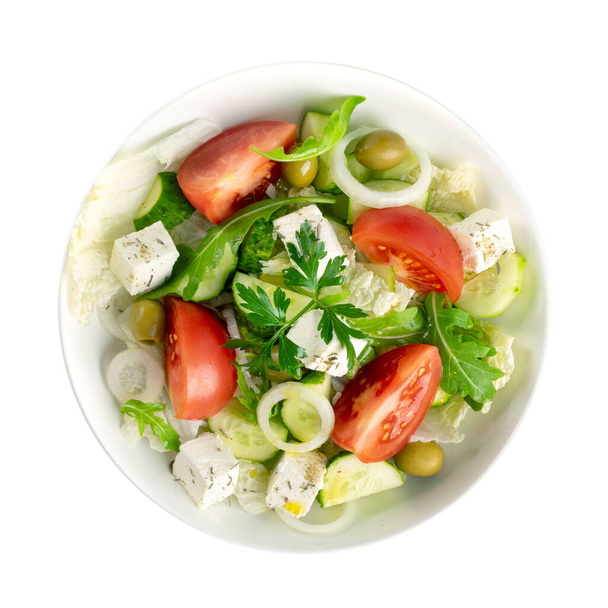 Görög saláta vagy horiatiki nagy darab paradicsommal, uborkával, hagymával, feta sajttal és olajbogyóval, fehér tálban, elszigetelt felülnézetben. Falusi saláta kockázott mozzarellával, arugulával, petrezselyemmel és olívaolajjal - Fotó, kép