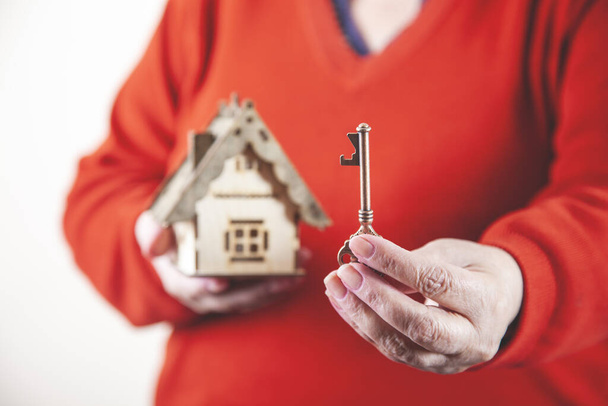woman hand holding house model and key on grey background - Photo, Image