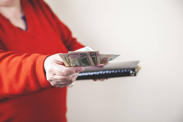 woman hand wallet and money on grey background - Zdjęcie, obraz