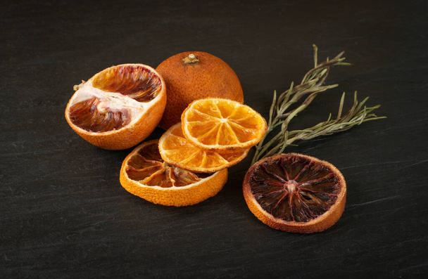Fette essiccate di arancia e arancia rossa su fondo naturale in pietra nera. Limone secco, mandarino e arancia siciliana da vicino
 - Foto, immagini