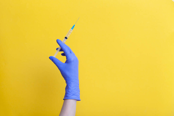 doctors hand in latex glove holding transparent syringe with vaccine - Фото, изображение