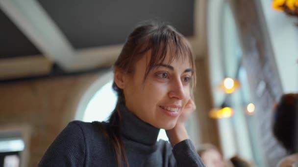 Retrato de mujer joven inteligente en vasos bebiendo café, sonriendo a la cámara, disfrutando de estudiar en el espacio de coworking o cafetería, utilizando wifi y computadora portátil
 - Imágenes, Vídeo