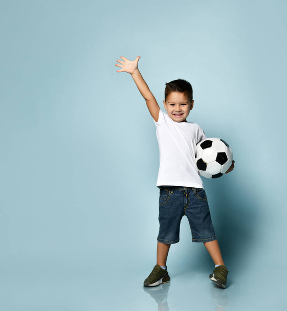 Cute boy playing football, happy child, young male teen goalkeeper enjoying sport game, holding ball, isolated portrait of a preteen smiling and having fun - Foto, imagen