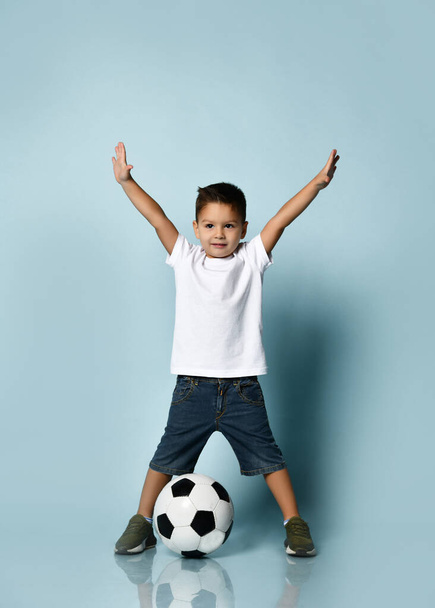 Cute boy playing football, happy child, young male teen goalkeeper enjoying sport game, holding ball, isolated portrait of a preteen smiling and having fun - 写真・画像