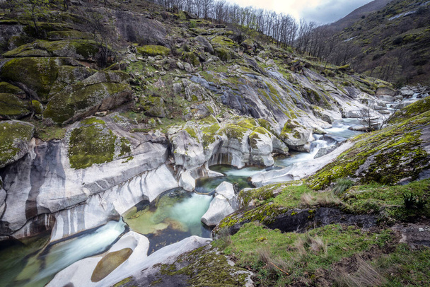 İki aşınmış dağdan oluşan güzel bir vadi bir nehre dökülür. - Fotoğraf, Görsel