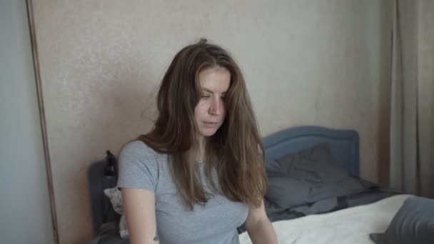 Girl artist sits on the bed and begins to straighten her hair - Πλάνα, βίντεο