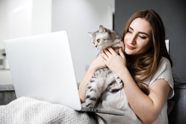Young Girl Works at Home with a Computer and Hug Cat - Фото, зображення