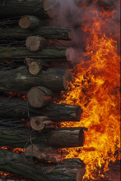 Fa határ egy réten, ami kandallóként világít az ünnepi boszorkányégetés alatt. Tűz, füst és forró parázs látható. - Fotó, kép