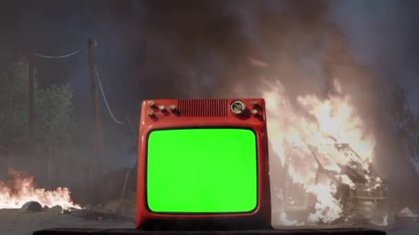 Retro-Fernseher mit grünem Bildschirm über einem Hintergrund mit einem brennenden Auto. Sie können den grünen Bildschirm durch das gewünschte Filmmaterial oder Bild ersetzen. Sie können es mit Keying-Effekt in After Effects oder jeder anderen Videobearbeitungssoftware tun. - Filmmaterial, Video