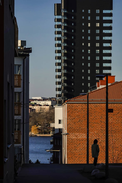 Stockholm, Sweden  Aperson in silhouette walking in Arstaberg down towards liljeholmskajen. - Photo, Image