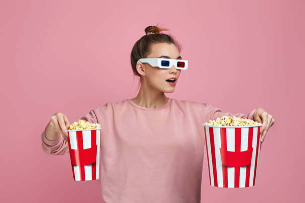 woman wearing red-blue 3d glasses and holding two bucket of popcorn - Foto, afbeelding