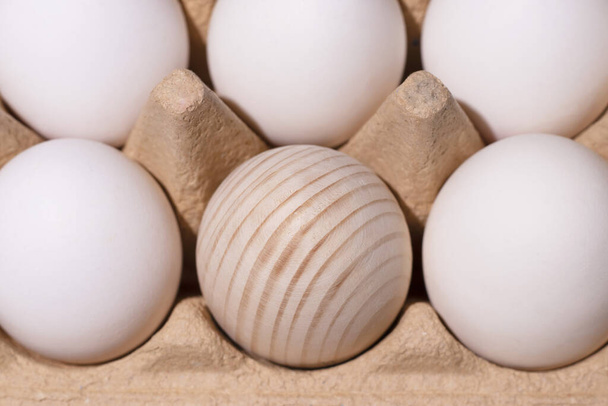 Білі яйця і одна дерев'яна крупним планом в упаковці
 - Фото, зображення