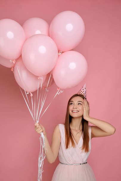 woman in birthday hat celebrating with pastel pink air balloons - Foto, afbeelding