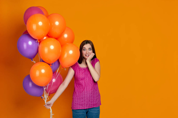 shy and embarrassed woman with bright colorful air balloons - Photo, Image